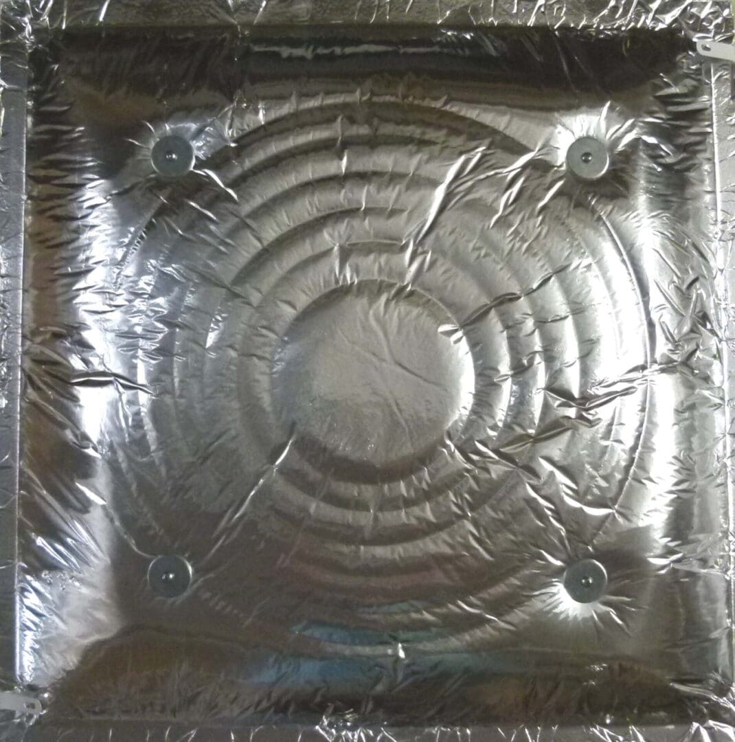A Universal Start Collar Back Pan with a square, metal design wrapped in plastic, featuring four circular raised elements evenly spaced near the corners.