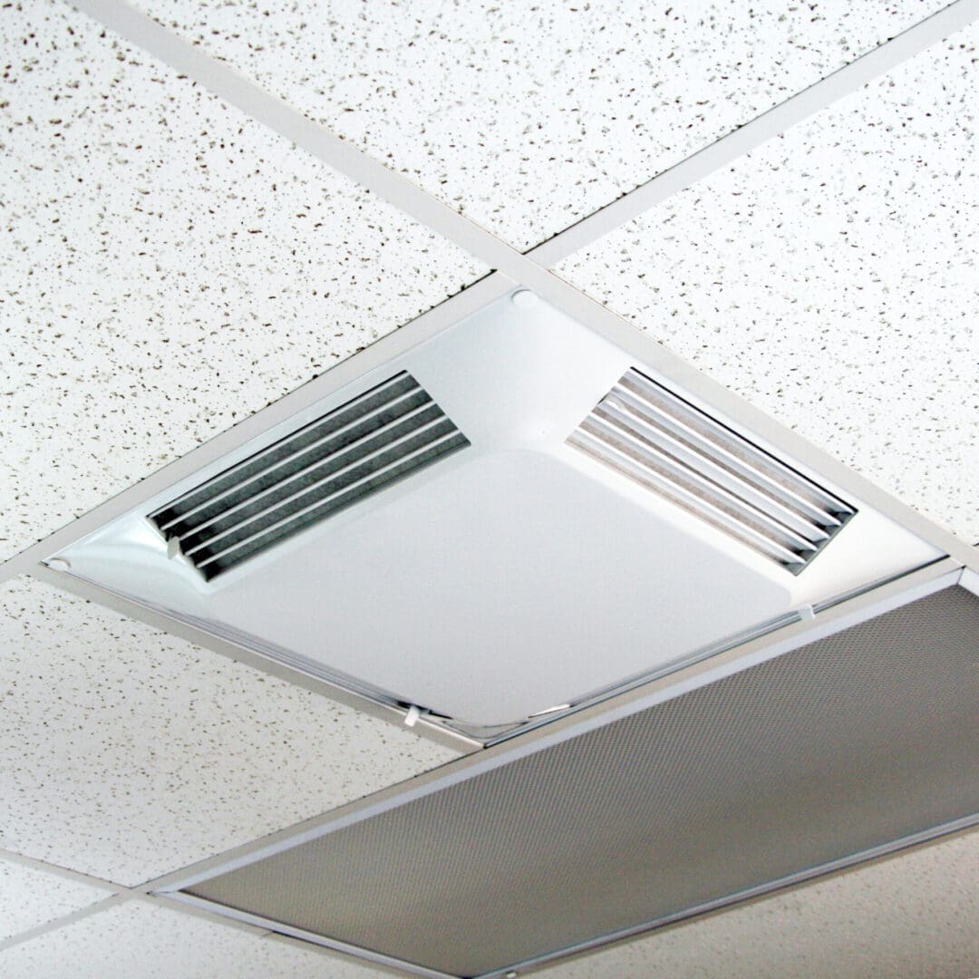 The Comfort First Filtered Diffuser, a square filtered air vent, is installed in a white tile grid pattern.